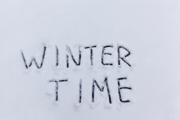 the words winter time drawn on the snow