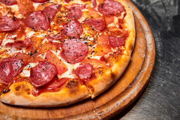 Pizza with sausages, tomatoes and cheese on the metal plate. Close-up, selective focus