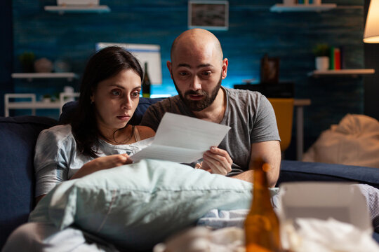Depressed couple feeling sadness stressed about high mortgage rates, worried tenants by warning notification for unpaid renter bank bills. Woman reading eviction notice document