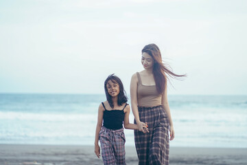 mother and daughter enjoying the holiday atmosphere by the beach hand in hand