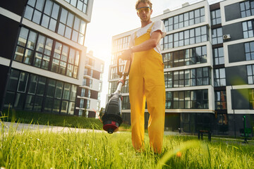 Fototapeta premium Beautiful sunshine. Man cut the grass with lawn mover outdoors in the yard