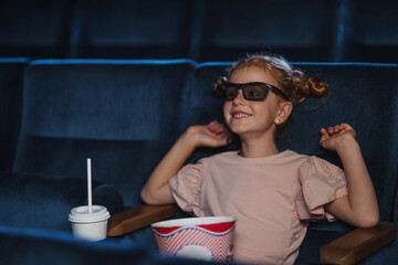 Happy small girl with 3d glasses in the cinema, watching film.