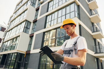 Modern city. Young man working in uniform at construction at daytime