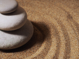 Fototapeta na wymiar Zen garden. Pyramids of white and gray zen stones on the white sand with abstract wave drawings.