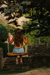 Gorgeous blonde woman enjoying on the swing during golden hour