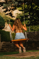 Gorgeous blonde woman enjoying on the swing during golden hour