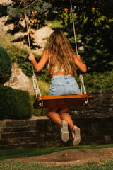 Gorgeous blonde woman enjoying on the swing during golden hour