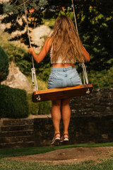 Gorgeous blonde woman enjoying on the swing during golden hour