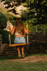 Gorgeous blonde woman enjoying on the swing during golden hour