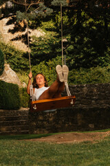 Gorgeous blonde woman enjoying on the swing during golden hour