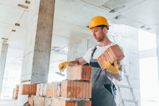 View From The Side. Young Man Working In Uniform At Construction At Daytime