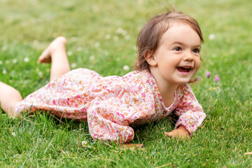 childhood, leisure and people concept - happy smiling little baby girl lying on grass in summer