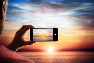 Smartphone camera photographing a sunset across the sea on vacation - Powered by Adobe