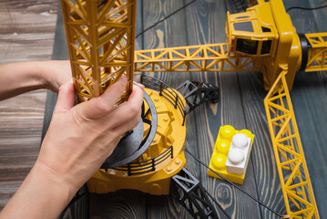 A girl is playing with a toy construction crane close up.