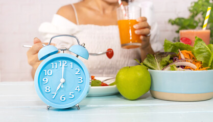 Close up of blue clock it timer for  woman restricted eating. Healthy foods between clock hands,...