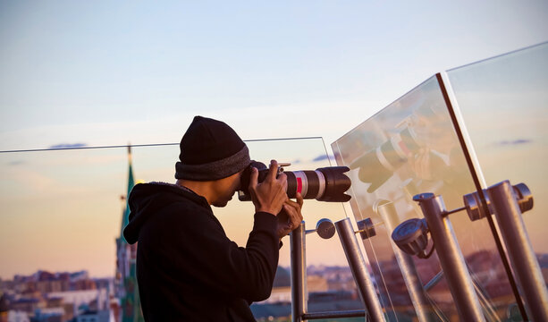 Back view of  Asian young man photographer using a camera takeing a picture of view in red square skyline  with sunset sky scene background in the, Moscow,Russia