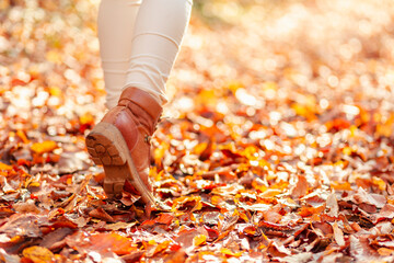 Woman walking through a path covered with fallen autumn leaves