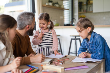 Father with three daughters indoors at home, drawing pictures.