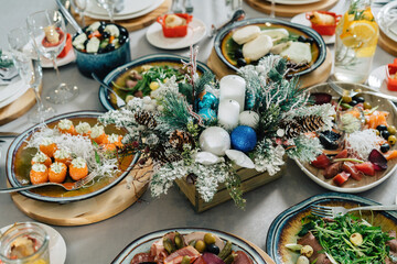 A beautiful Christmas table is set for a family dinner. Composition of twigs and cones in the middle of the table.