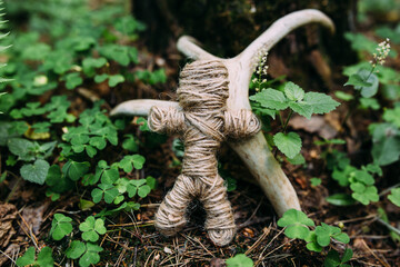 A woven voodoo doll of threads and bones in a ritual in a mysterious forest.