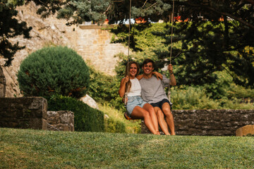 Beautiful couple enjoying the sunset on a swing hanging from a tree