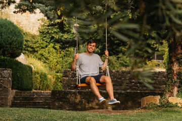 Young boy enjoying on the swing during golden hour