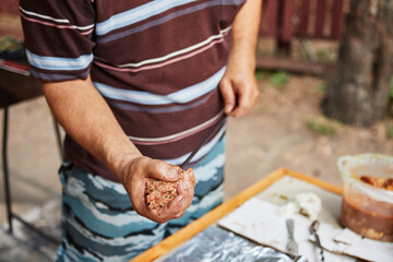 man prepares lula kebab in nature