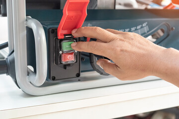 Hand pressing on Electromagnetic start switch table saw