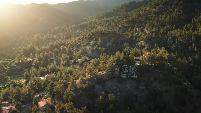 Sunrise town village on slope hill scenery in Cyprus. Aerial sunset mountain area houses green trees on mount Olympus in Troodos. Beautiful nature landscape cityscape. Travel destination. Drone flight