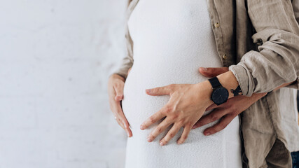 Pregnant woman in a white dress with her husband in a living room