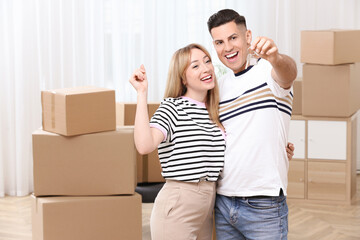 Happy couple with key from their new house indoors