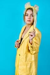 portrait of  young woman in yellow jacket and  headband. yellow background