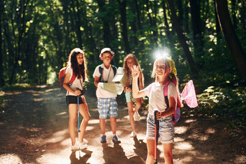 Posing for the camera. Kids strolling in the forest with travel equipment