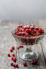 Frozen red currants in a glass vase on a rustic wooden table. Close-up.