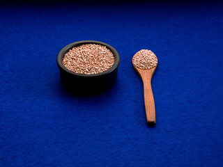 A closeup shot of a bowl and a spoonful of quinoa on a blue background