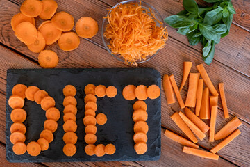 Diet, health, vegetable concept. Different cuts of carrots on a wooden table, word diet on black cutting board