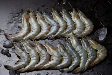fresh shrimp in a row on black wooden table
