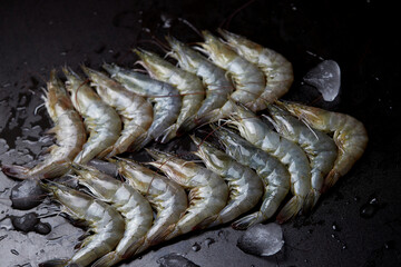 fresh shrimp in a row on black wooden table