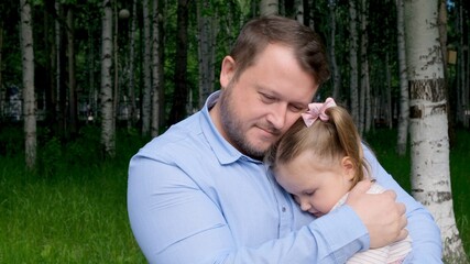 strong Father holds on his arms a sweet daughter, 3 years old, hugs her and hugs her. The concept of parenting, overcoming problems in the relationship between father and daughter, illness, fear for