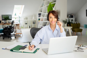 Attractive businesswoman wearing headset while having online meeting. Customer service assistant...