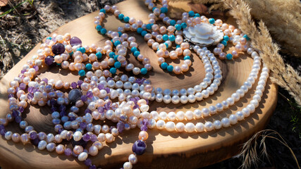 Variety of iridescent natural pearl and amethyst beads on a wooden background. Retro composition close up. Natural mineral. 