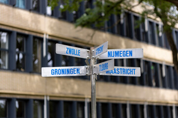 Direction sign in front of school building pointing at several Dutch cities such as Zwolle,...