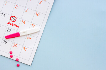 Ovulation home test and pills on calendarwith red mark