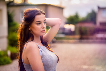 Young beautiful woman in gray dress at sunset