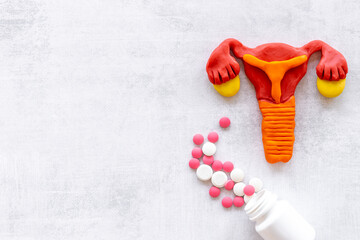 Women health concept - female uterus and ovaries model with medical pills