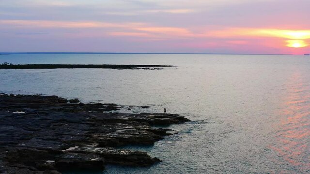 Person Standing Near Rocky Nightcliff Foreshore At Sunset In Darwin City, Northern Territory, Australia. - Aerial Drone Shot