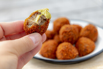 Selective focus of a man hand with bite bitterballen, Dutch meat-based snack served with mustard,...