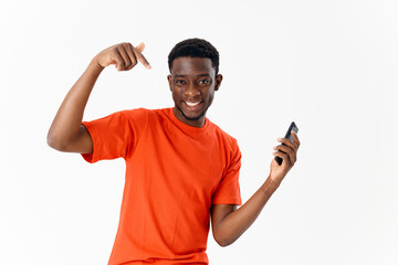 Fototapeta premium Cheerful man of african appearance with a phone in his hands gesturing with a finger light background
