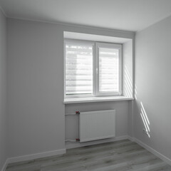 Contemporary apartment. Light interior of empty renovated room. Heating battery under window on wall. Nobody.