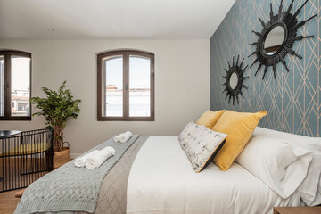 King size bed with yellow cushions with black mirrors on the wall in a vacation rental studio